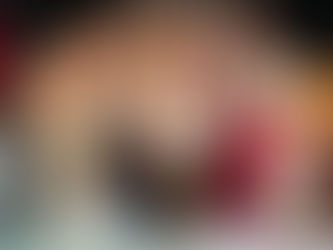 A large group of smiling 5th grade girls poses confidently on stage and in front of it after participating in a tznius fashion show. They are dressed in stylish, modest outfits with a variety of colors and patterns. The background features a school stage with a black curtain and a visible microphone stand.