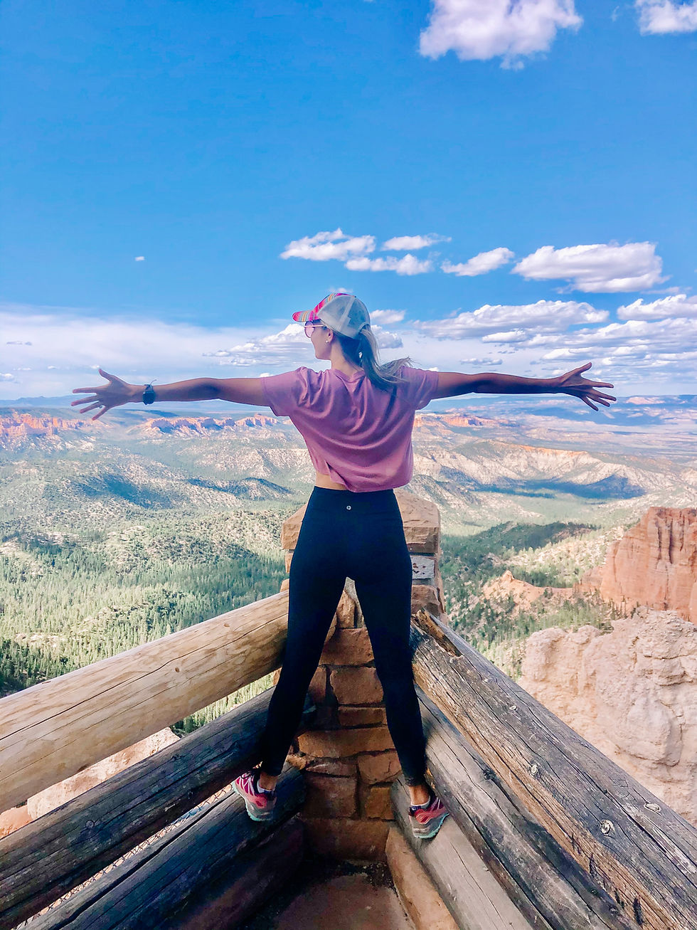 Young woman hiking with arms stretched over mountain range