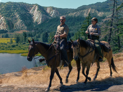 Eric Bana and Lily Santiago riding horses in a national park.