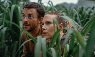 Jonathan Bailey and Scarlett Johansson hiding in tall grass.