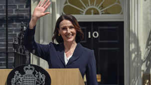 Suranne Jones waving her hand and greeting people behind a podium.