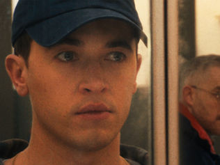 Tom Blyth and Russell Tovey exchanging looks in the mirror.