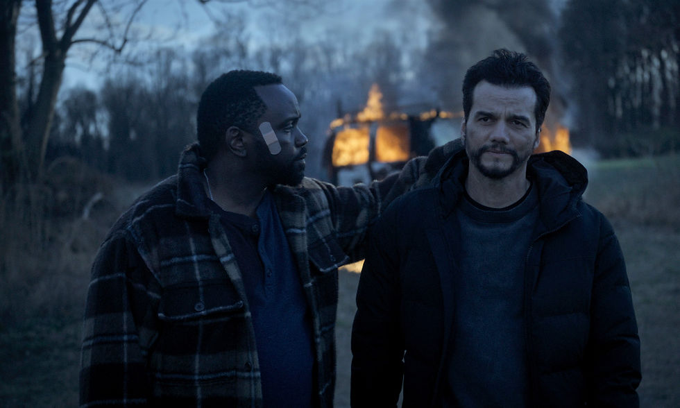Brian Tyree Henry and Wagner Moura walking away from a burning van in the woods.