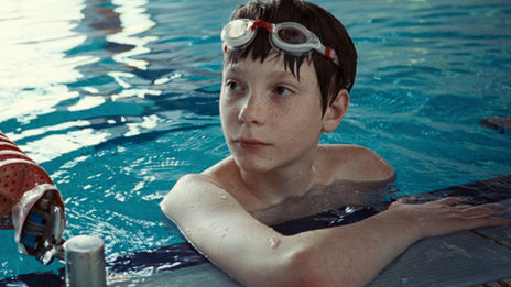 Everett Blunck, rocking swim goggles, hanging out in the water at the edge of a pool.