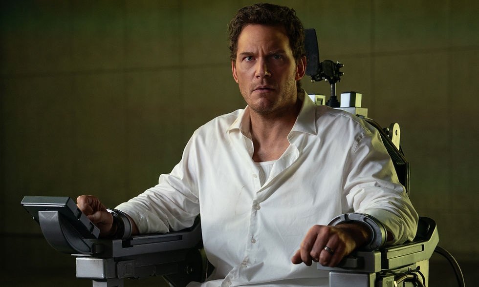 Chris Pratt sitting on a metal chair, handcuffed to it.