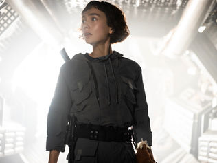 Sydney Chandler inside a spaceship, standing in front of blinding white light.