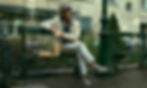 Michael Fassbender sitting on a park bench, holding a burger