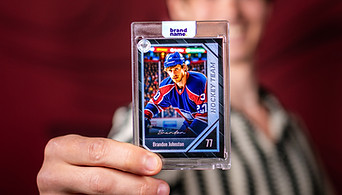 A man holding up a custom trading card with his photo