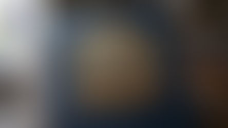 Blue leather book with ornate gold emblem: "Ultimate CBSE Class 12 English Study Guide." Pens and books in a library setting.