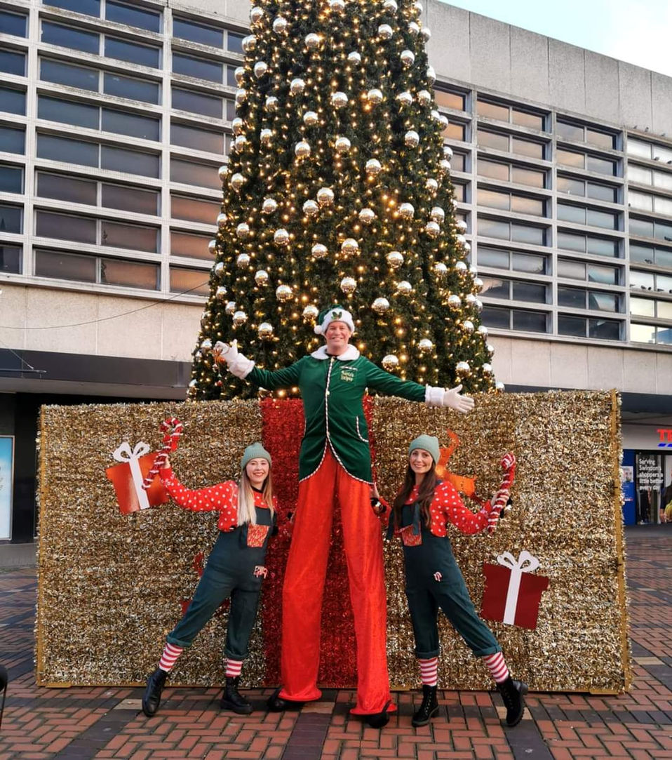 Festive stilt walker in Christmas costume entertaining guests at a holiday event – perfect for Christmas party entertainment, winter festivals, and seasonal event hire in the UK.