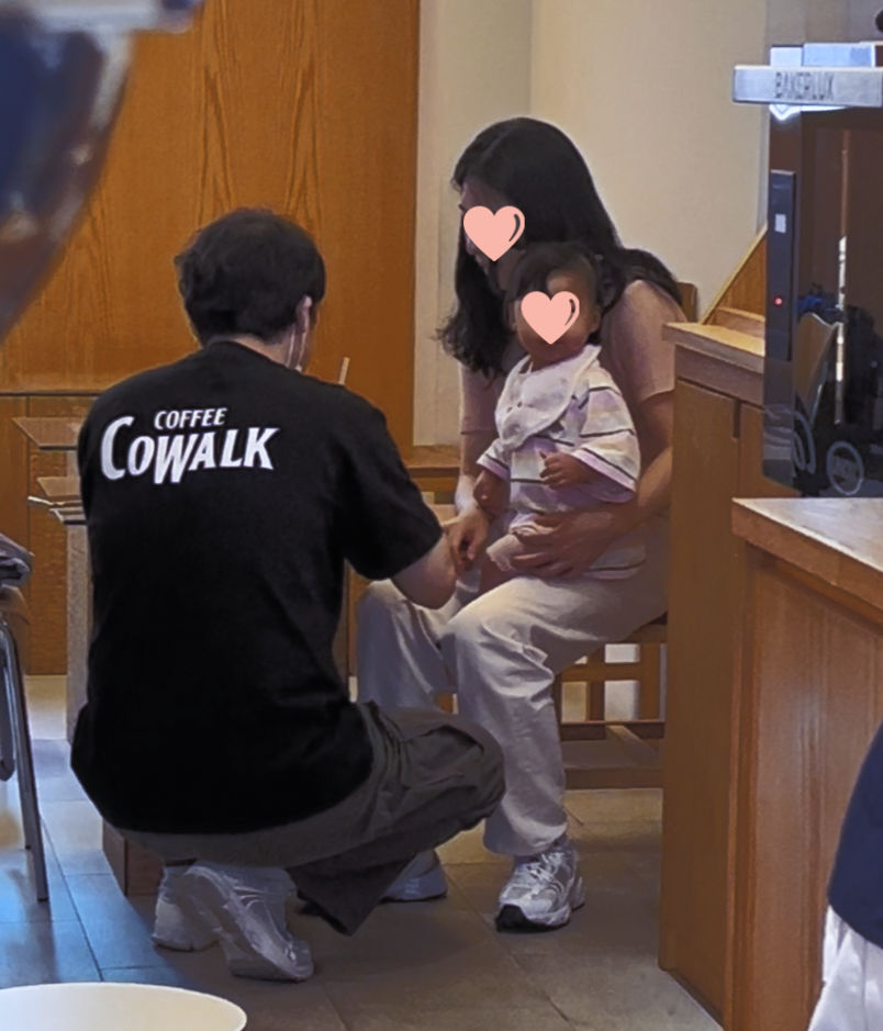 The local cafe owner feeding his daughter while she sits on his wife's lap.