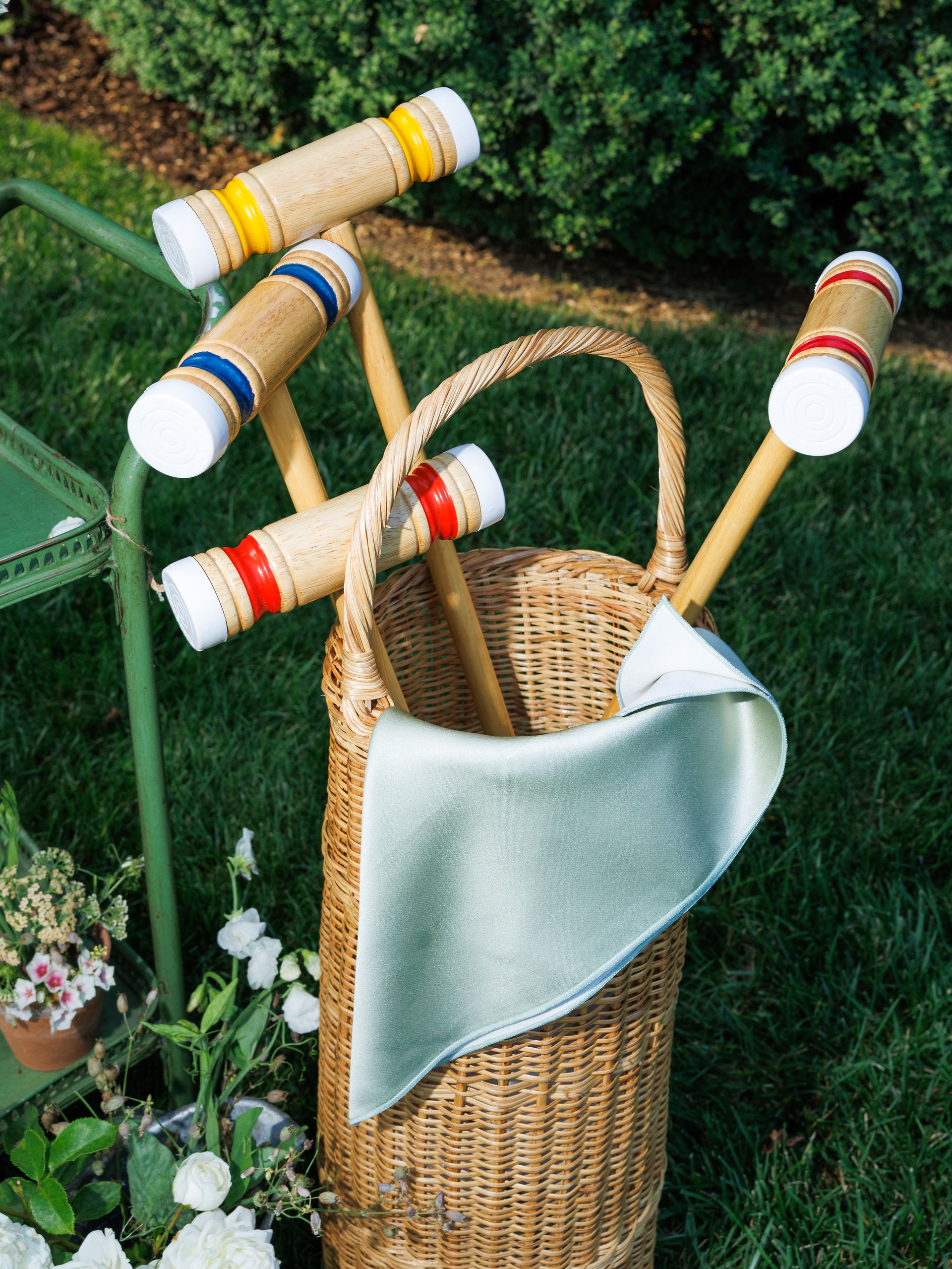 An editorial detail shot of croquet clubs at an outdoor summer wedding