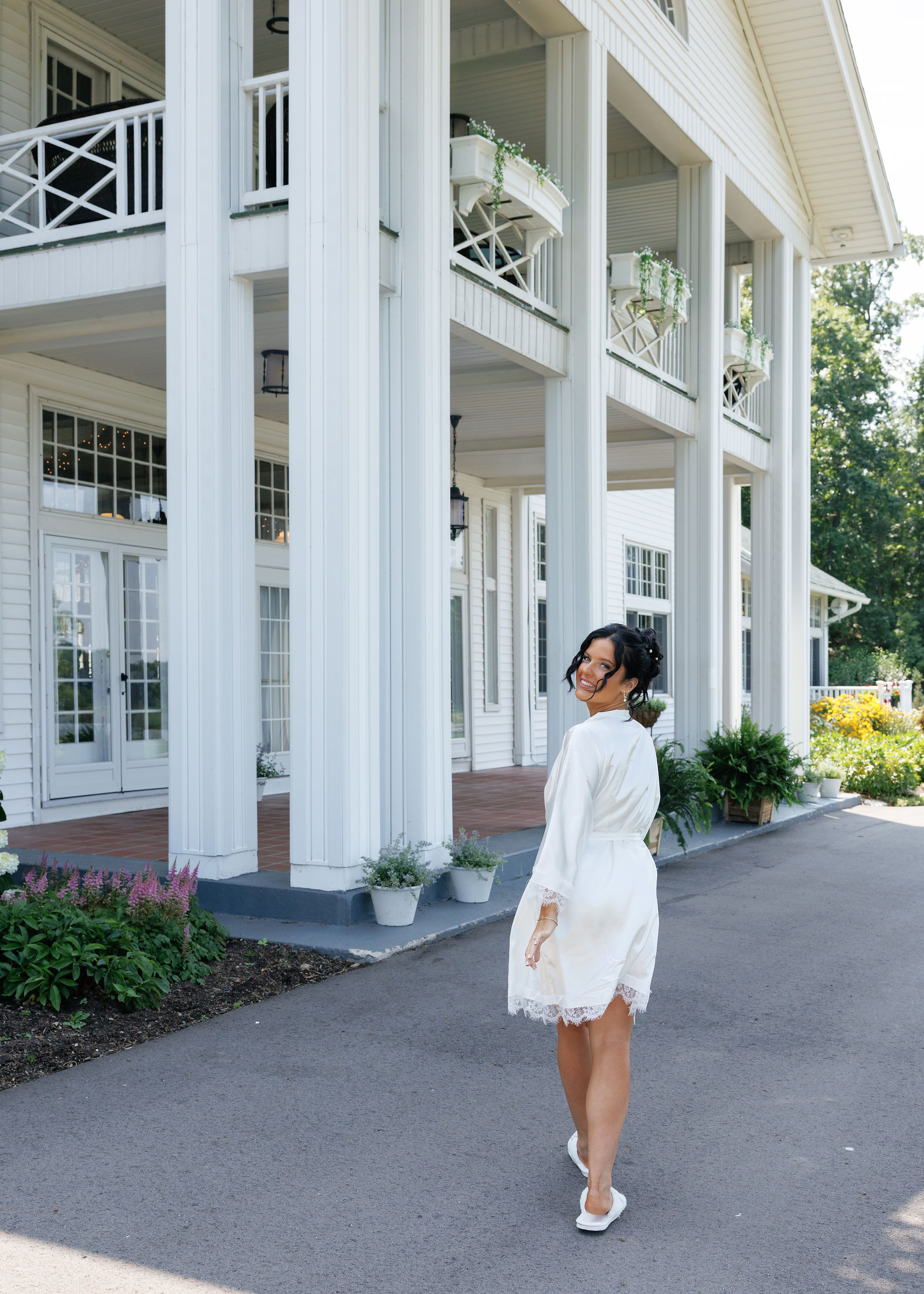 A bride walks away from the camera in front of a beautiful venue with a balcony and a porch