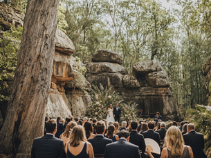 Outdoor wedding ceremony in the Rock Cathedral amphitheater, bride and groom say vows in front of their seated guests.