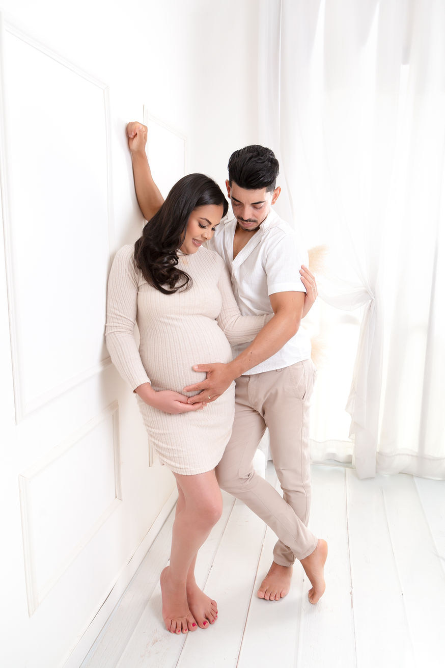 Foto de ensaio gestante com casal em sintonia no cenário sala – roupas claras
