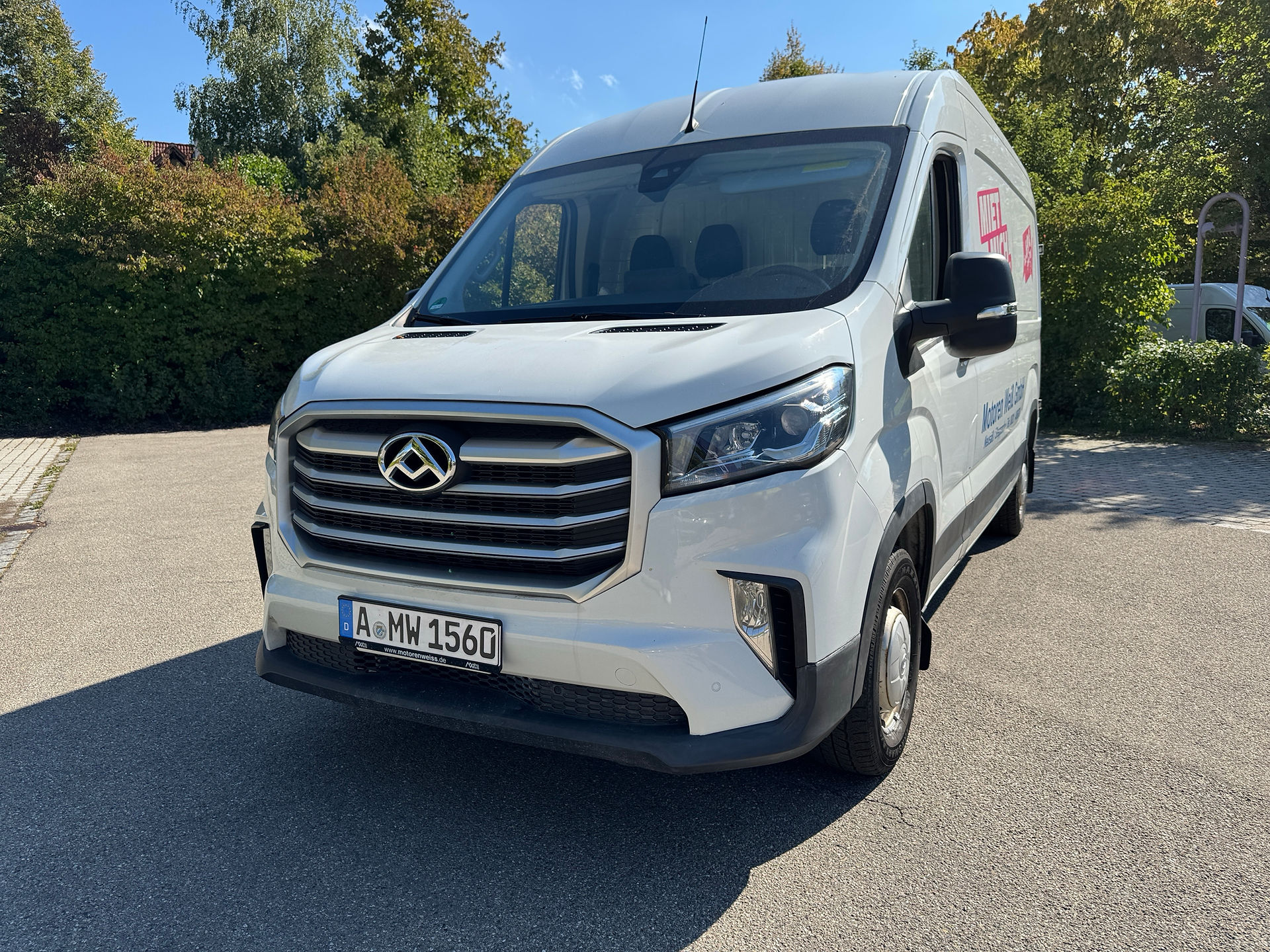 Ein Maxus Deliver 9 Transporter steht auf einem Parkplatz mit der Aufschrift Miet mich von Motoren Weiß