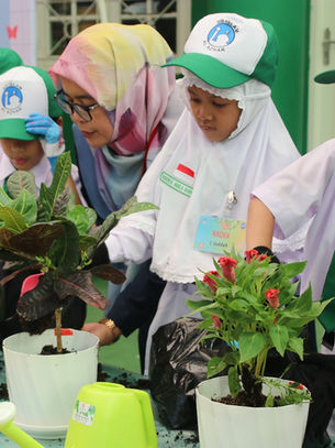 Murid dan guru sedang menyiram tanaman