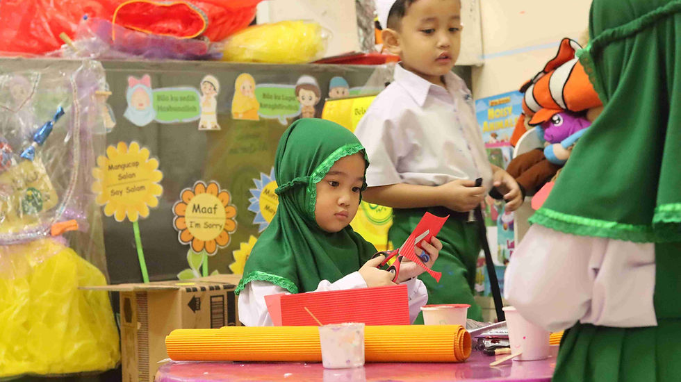 Salah seorang murid TK sedang menggunting bahan kostum