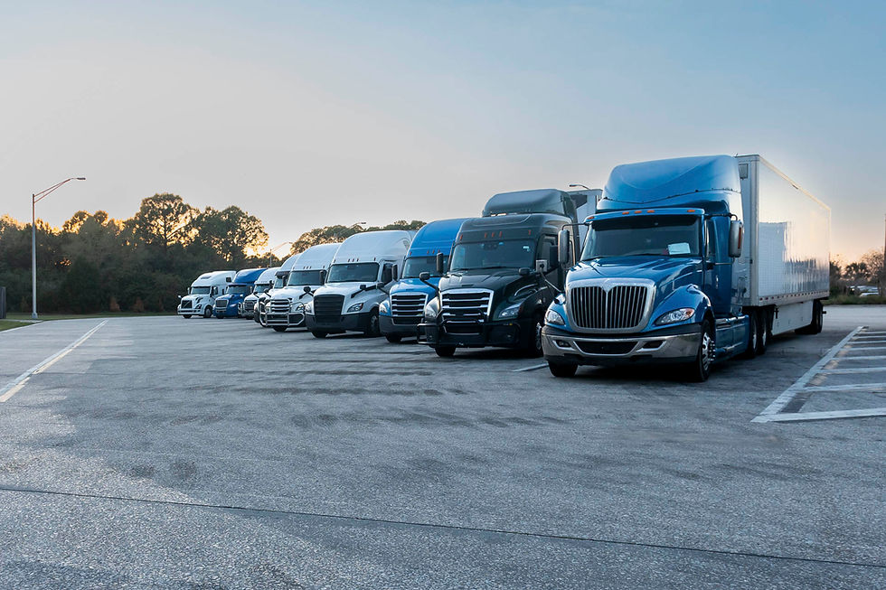 Row of blue and black semi-trucks parked in a spacious lot.