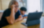 A senior woman reads her tablet screen while sitting next to her grandson