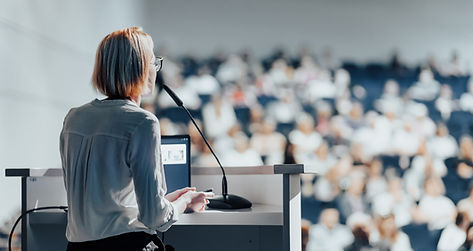 Female speaker giving a talk on corporate business conference. Unrecognizable people in au