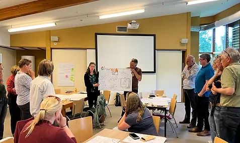 Team aan het werk met visuele communicatie waarbij grote tekening wordt getoond aan elkaar