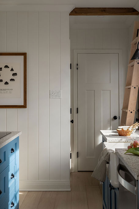 Détail d’une cuisine avec rangements blancs, mobilier bleu et échelle en bois