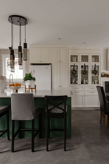 Cuisine blanche avec îlot vert, tabourets et luminaires suspendus