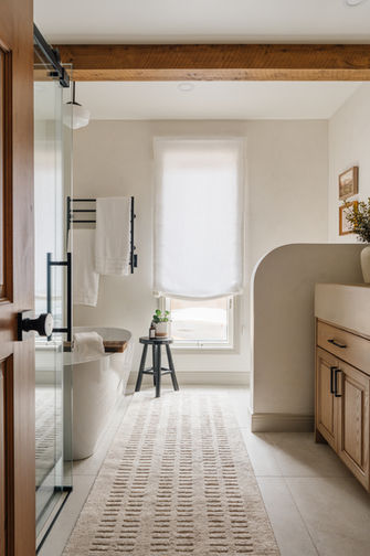 Salle de bain écoresponsable avec baignoire autoportante, douche vitrée, vanité en bois sur mesure, matériaux durables et lumière naturelle.