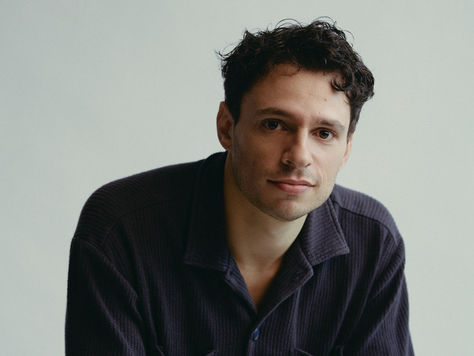 A caucasian man with dark hair and a navy blue shirt