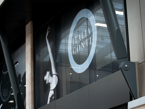 The Italia Conti round logo sign on the glass of the front of the Italia conti building - a modern metal and glass design