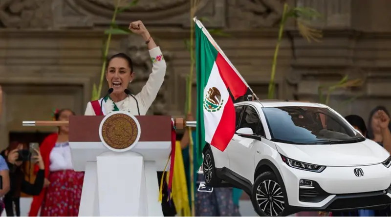 The picture shows a Mexican president at a podium with his fist raised, another person next to him and a new Mexican car with the Mexican flag