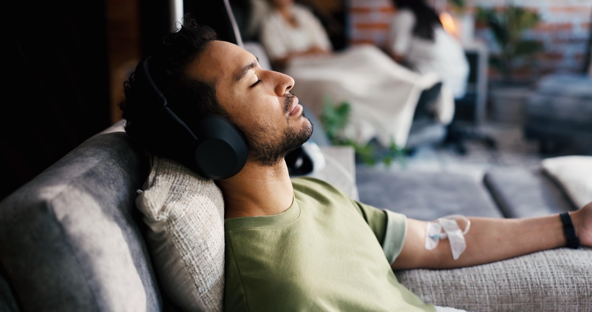 A young man relaxing with headphones while receiving an IV infusion