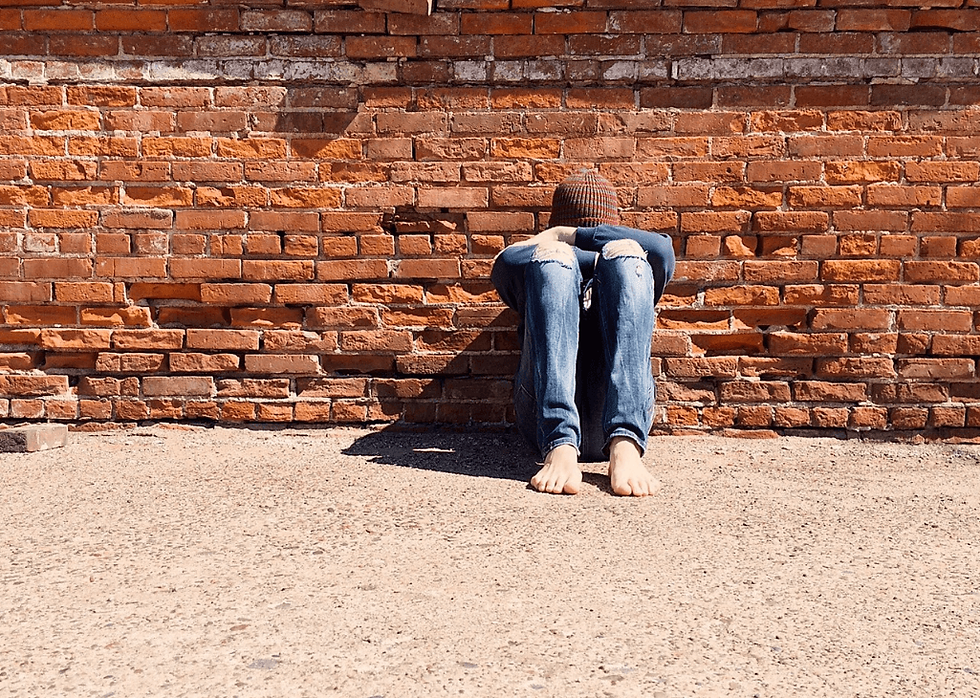 A picture of a young boy sitting in isolation with his head bent on his knees.