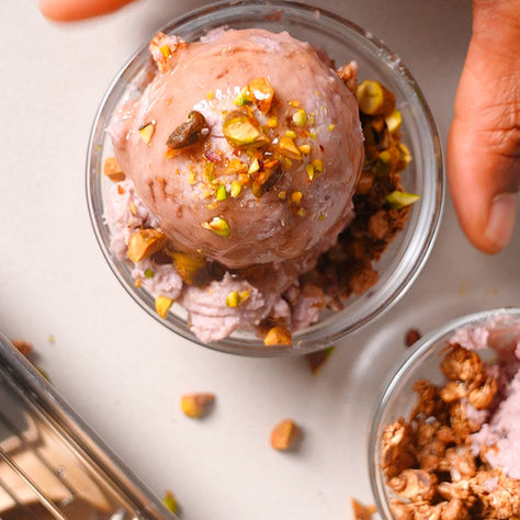Ube purple sweet potato ice cream topped with pistachios and honey sitting on a counter