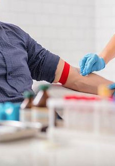 Phlebotomy student preparing an arm for blood draw.