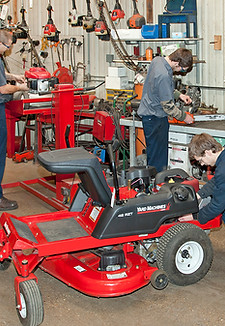 Three students working on individual small engines.