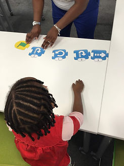 Beautiful black girl with bead in her hair taking part in an unplugged coding activity in Wimbledon.