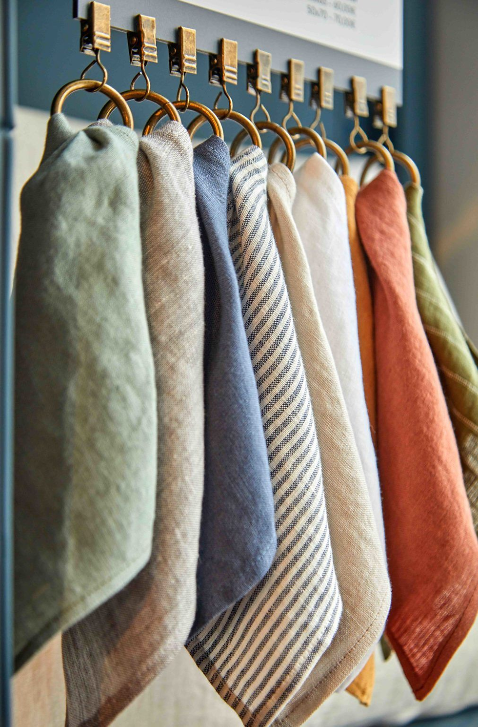 Colorful napkins hang on metal rings; blue, striped, earthy tones create a cozy feel. Background is soft-focus neutral.