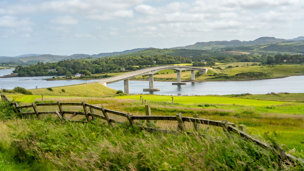 Harry Blaney Bridge crossing Mulroy Bay in Donegal, with green fields and wooden fence in foreground