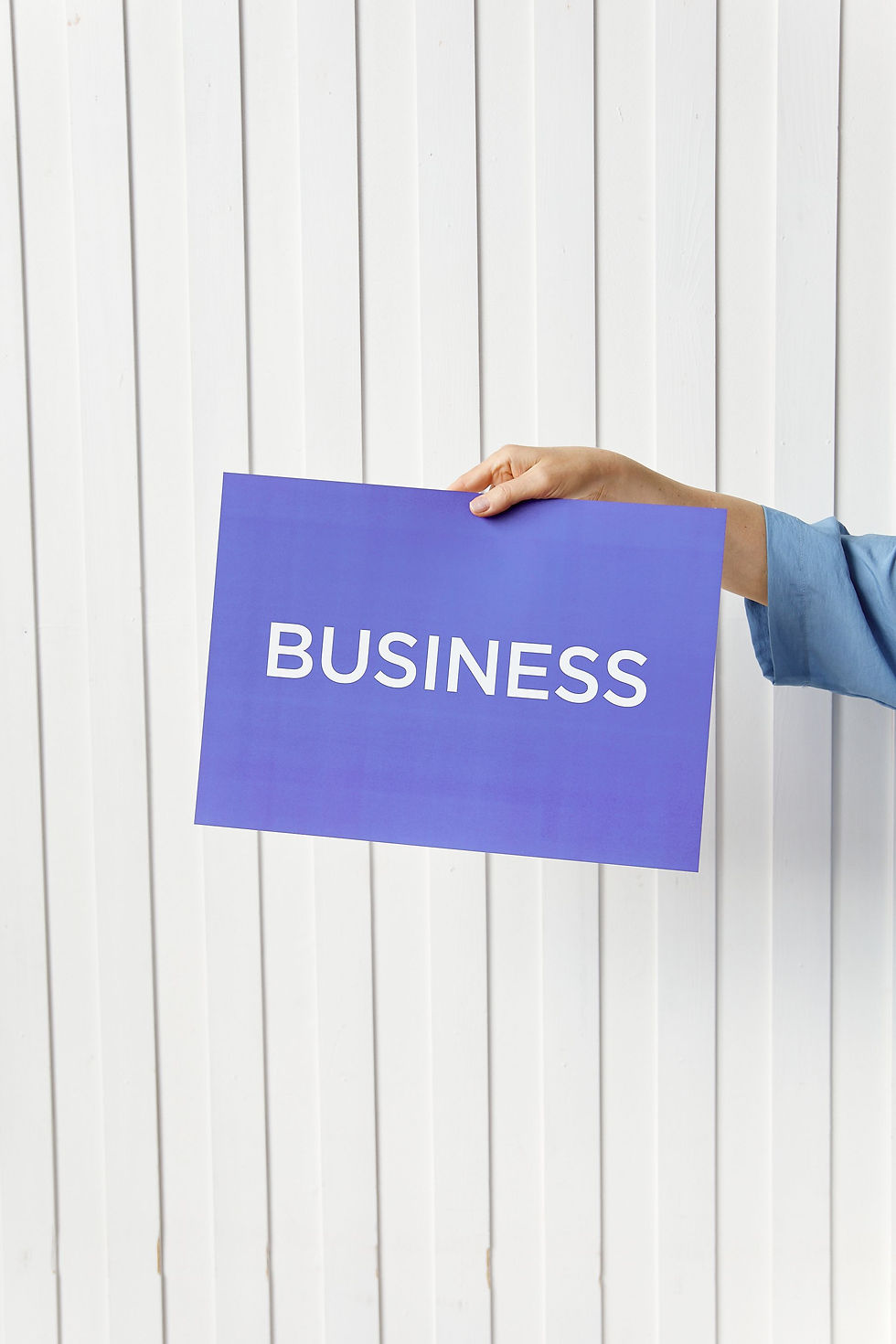 Hand holding a blue sign that says BUSINESS