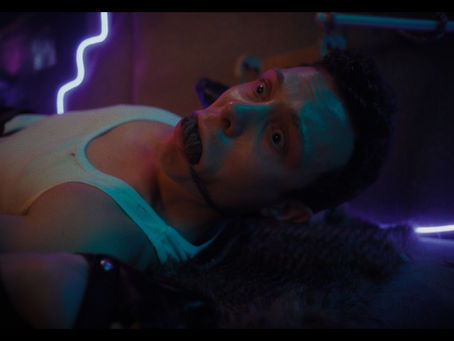 a white man wearing a white vest is strapped down with a gag in his mouth and neon lights