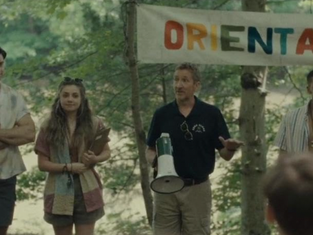 A group of six people are standing in front of a background of trees with a banner that reads orientation in rainbow colours.