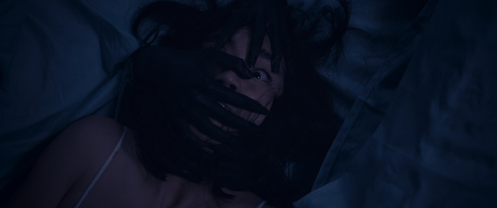 black hands cover the face of a woman who looks terrified