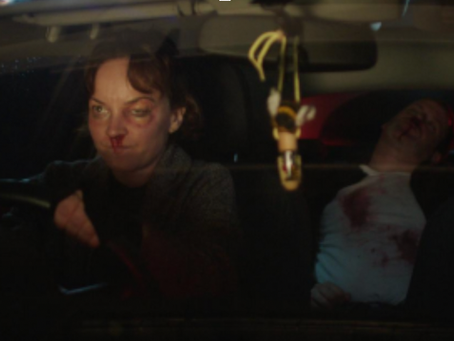 a woman with a bruised eye and a bloody nose is driving a car. in the back seat is a man passed out and bloody