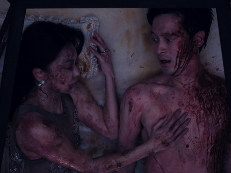 a man covered in blood is lying next to a woman who is also covered in blood