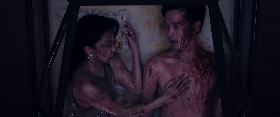 a man covered in blood is lying next to a woman who is also covered in blood