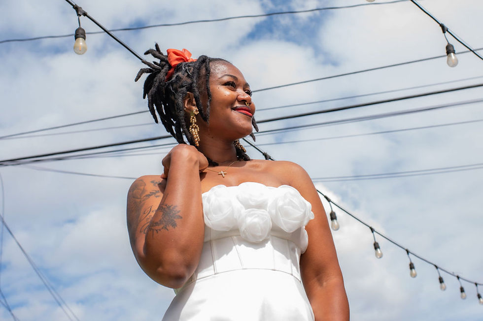 Smiling woman with dreadlocks in white top under string lights