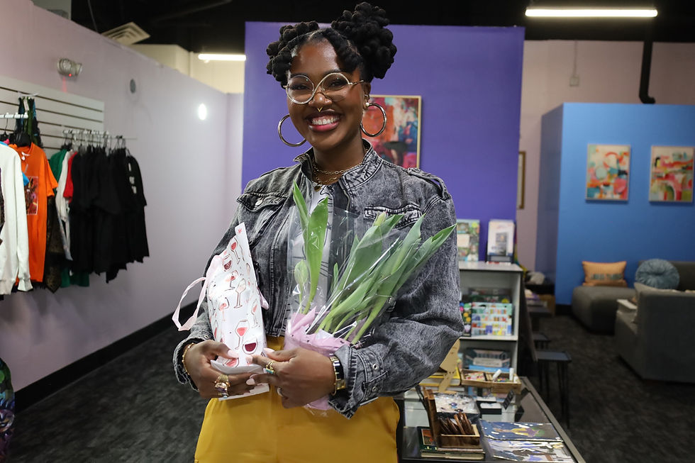 Smiling woman in a store holding a plant and gift bag