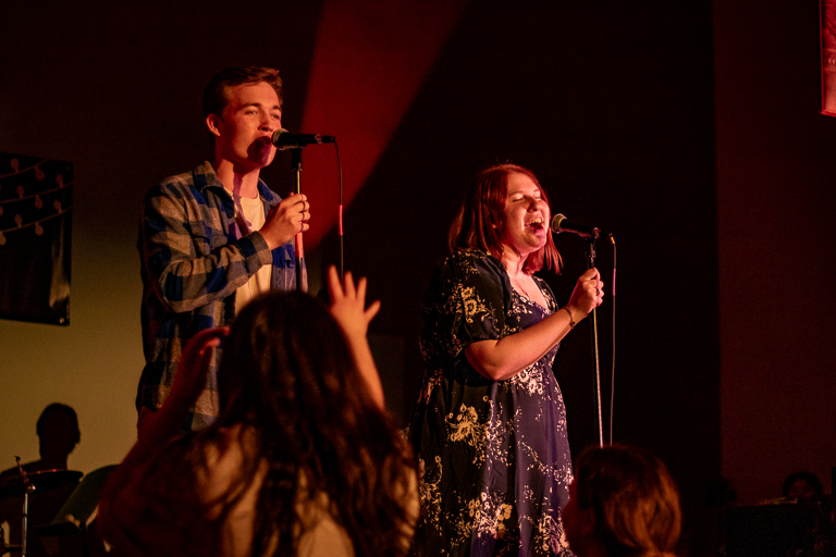Photo of man and woman singing at a concert